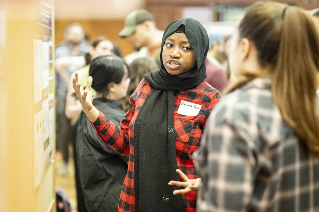 A woman gestures as she talks to people.