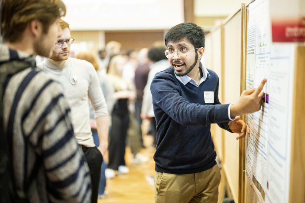 A man points to a board while explaining something to another person.