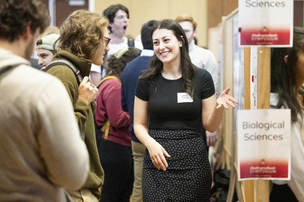 A woman smiles and talks to a small crowd.