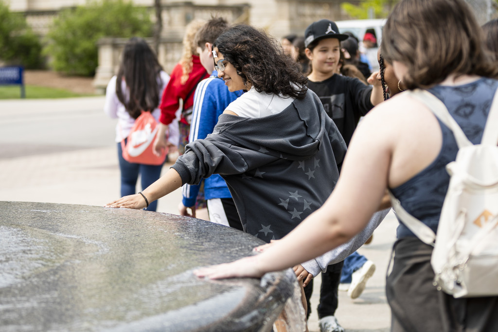 Children dip their hands in a round fountain.