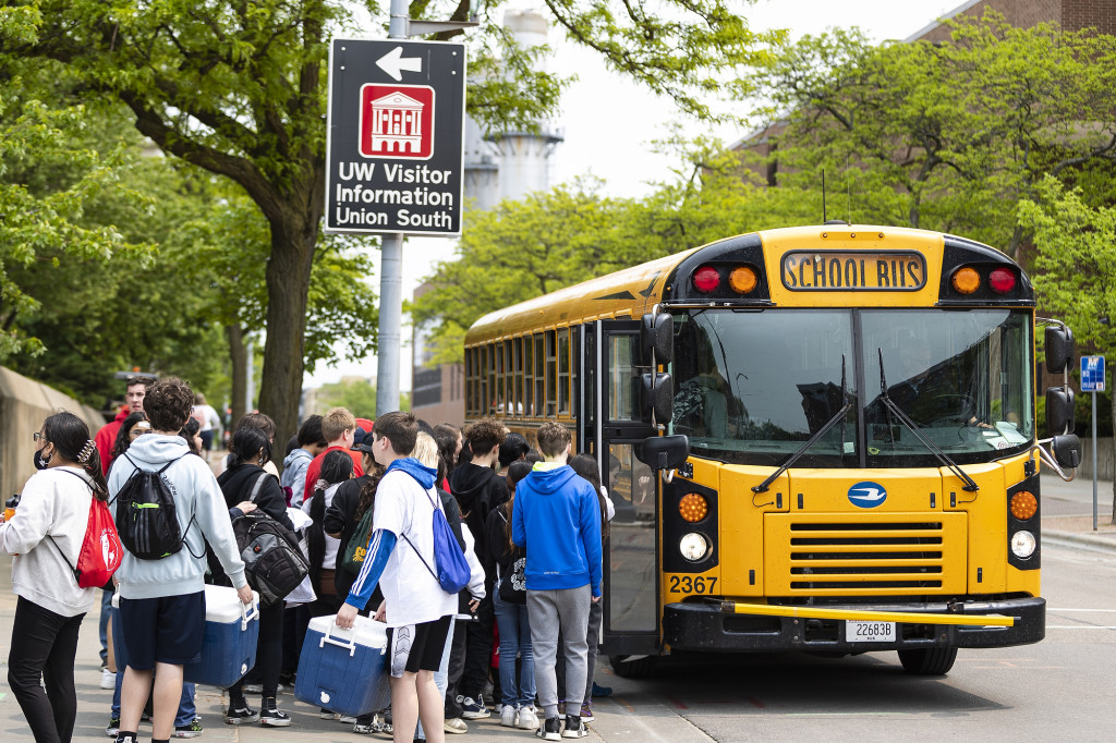 Kids line up to get on a bus.