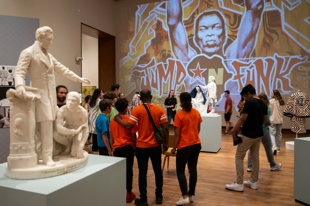 People stand around looking at a sculpture.