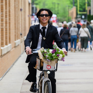 A person rides a bike with flowers in the basket.