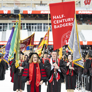 A group of people carrying a large red banner walk into the stadium.