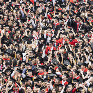 Row after row of happy people wearing graduation gowns are pictured.