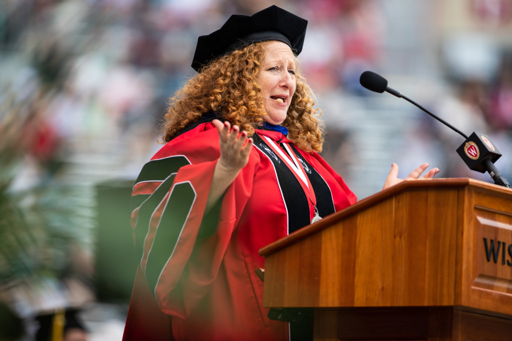 A woman gestures while she speaks at a podium.