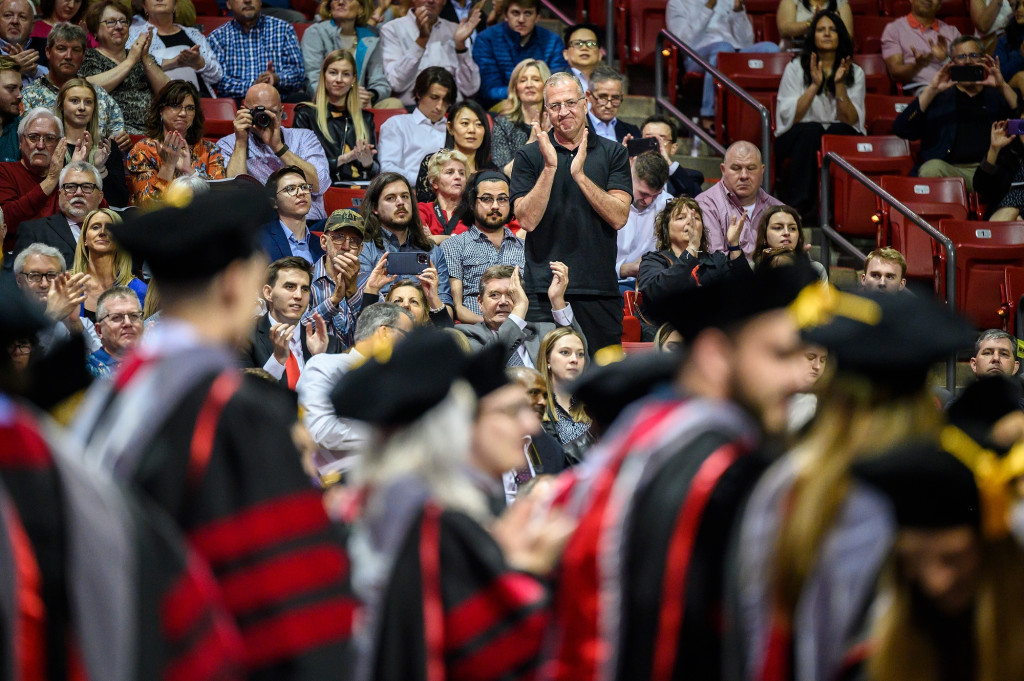 A man looks on as his daughter crosses the stage.