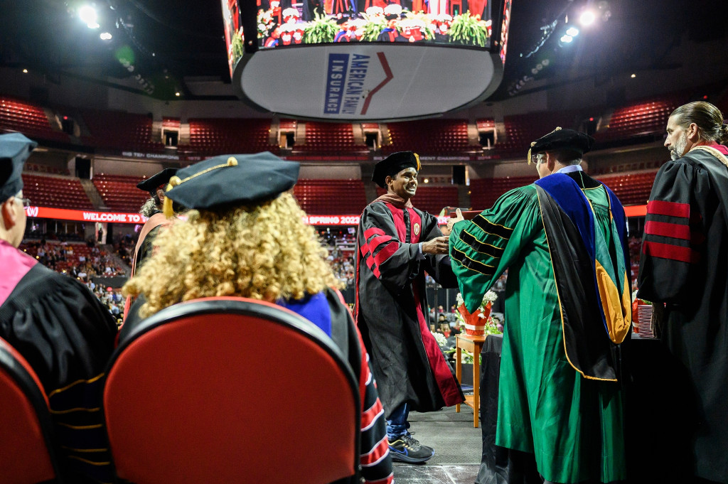 People wearing graduation robes line up on the stage.