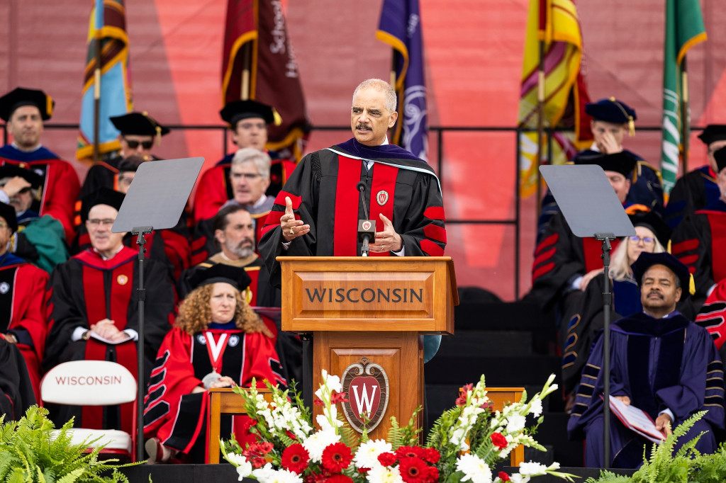 A man speaks at a podium, with people sitting behind him.