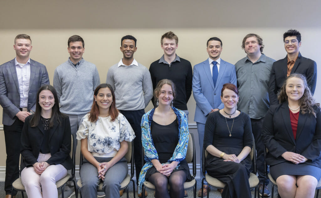 Twelve people are pictured looking at the camera, front row seated and back row standing.