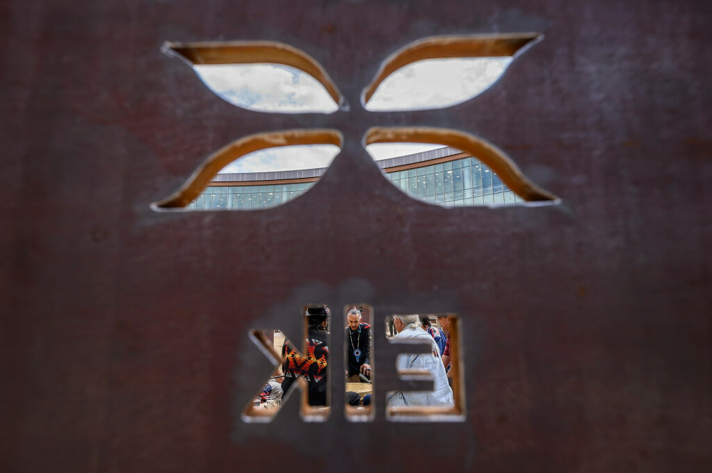 As seen through the Elk clan sculpture, Justice Green, a member of the Ho-Chunk nation, drums.