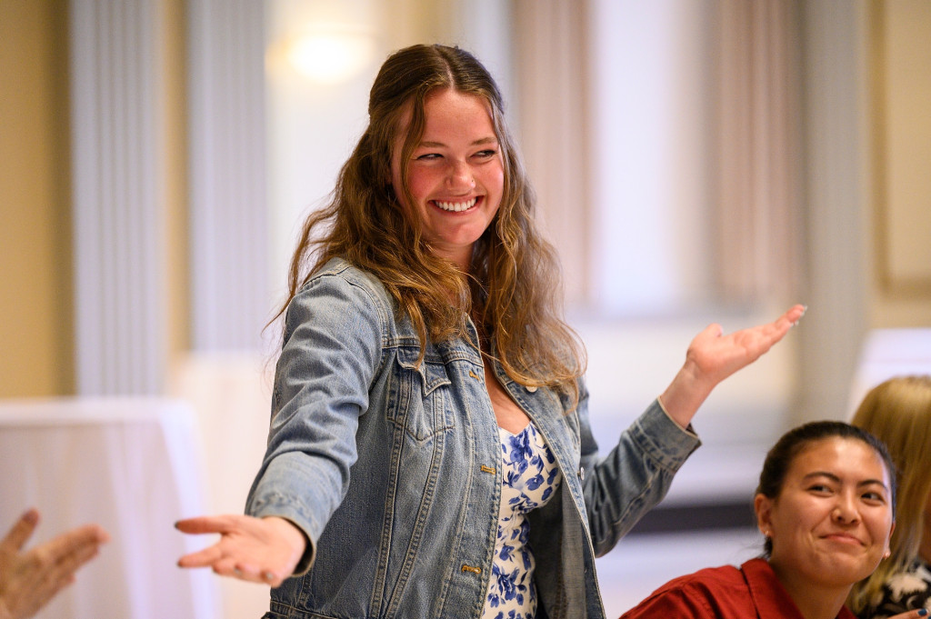 Karly Scholz stands and smiles with her arms wide in an open gesture.