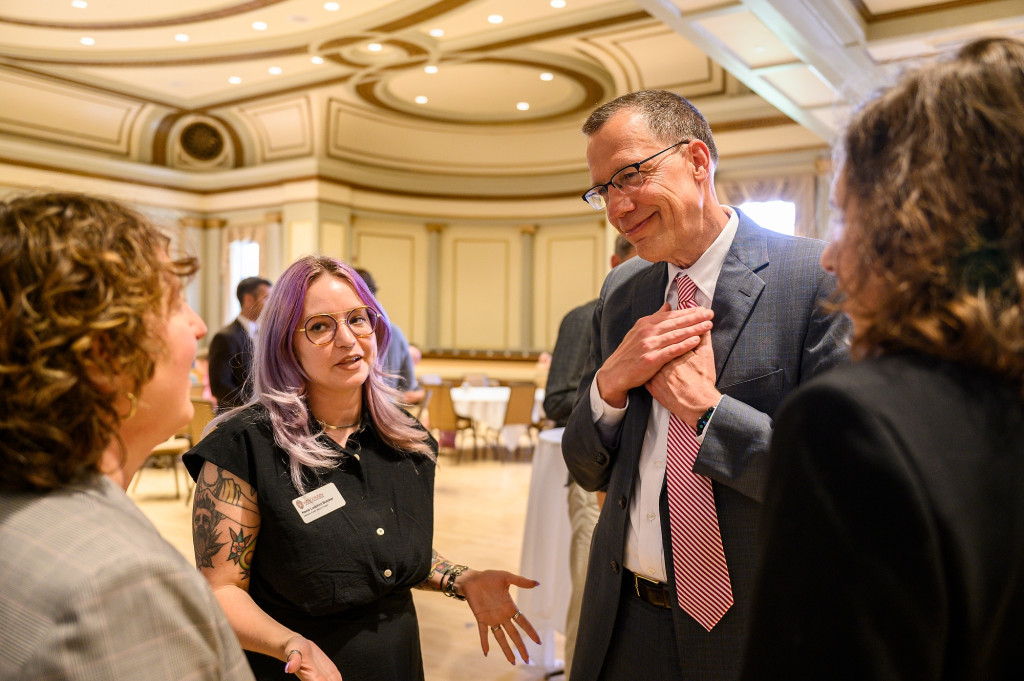 Karl Scholz places his hands on his heart in appreciation while listening to a conversation.