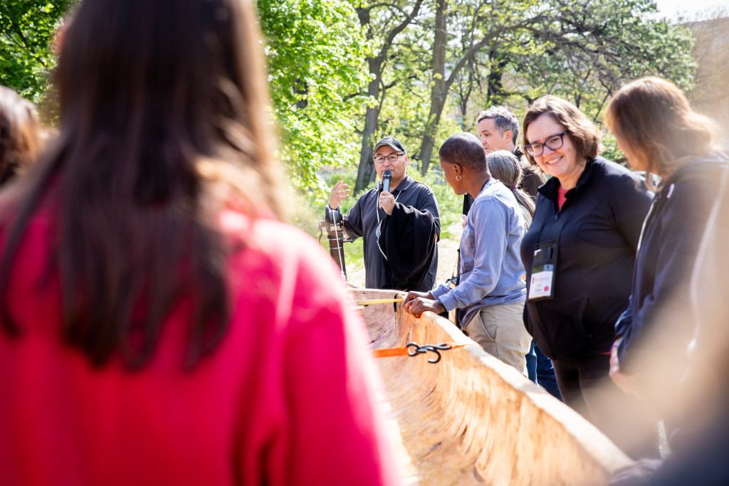 A group of people gather around a canoe.