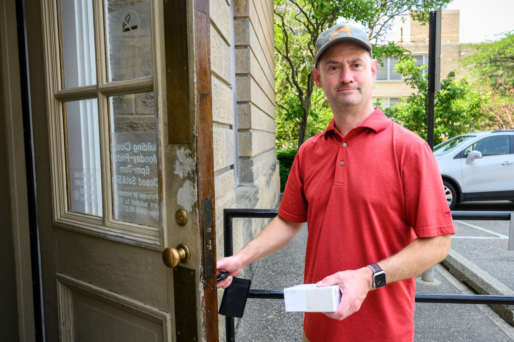 A man in a red shirt opens a door.