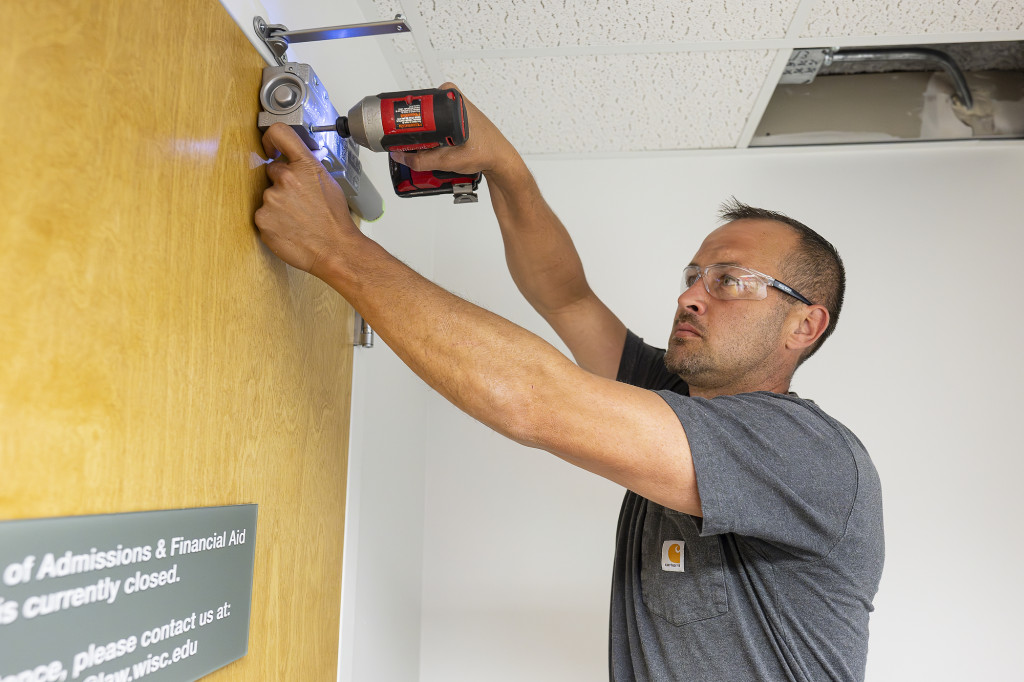 A man drills a screw into a door.