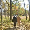 Two people walk through a wooded park.