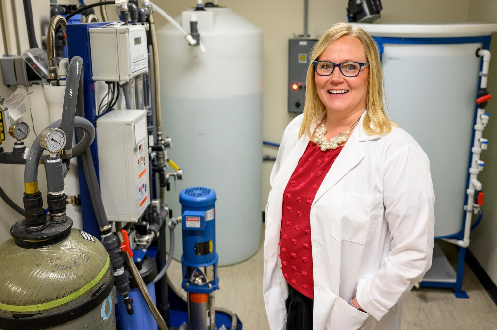 A woman in a white lab coat smiles for the camera.