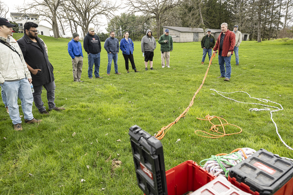 A man pulls on a rope with students watching.