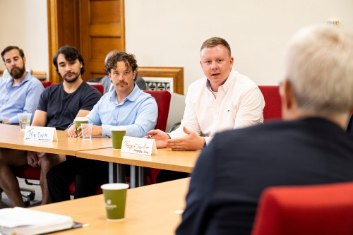 Keegan Trevillian, undergraduate student, Wisconsin Army National Guard member and president of Student Veterans of America, asks a question of Secretary McDonough while seated at a conference table.