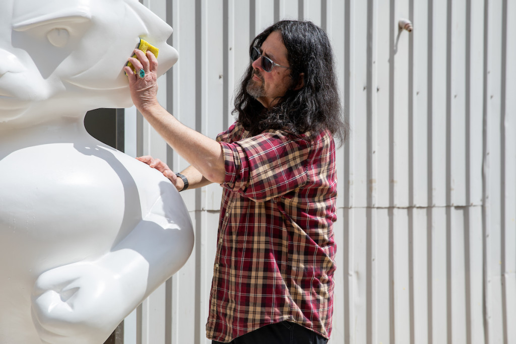 A person washes a plain White Bucky Badger statue