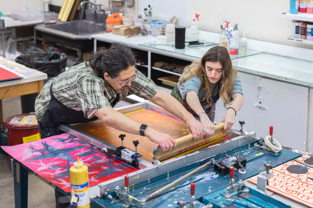 Two people work at a print machine.