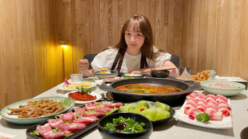 A woman sits at a table loaded with food.