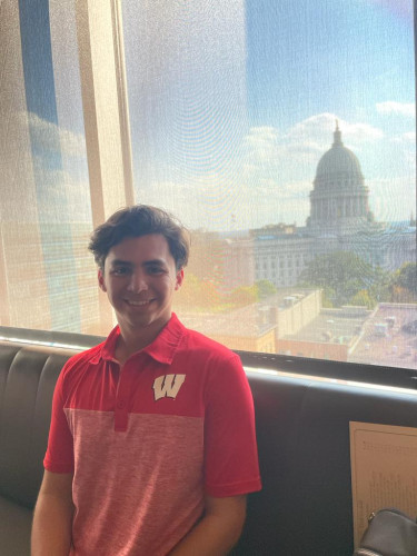 A man smiles for the camera with the Capitol building in the background.