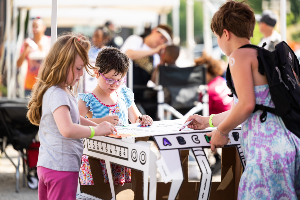 From left to right, Gabby, Lilly and Sophia Henning of Sun Prairie decorate a cardboard cutout of a school bus at a table sponsored by First Student, a local bus transportation company.