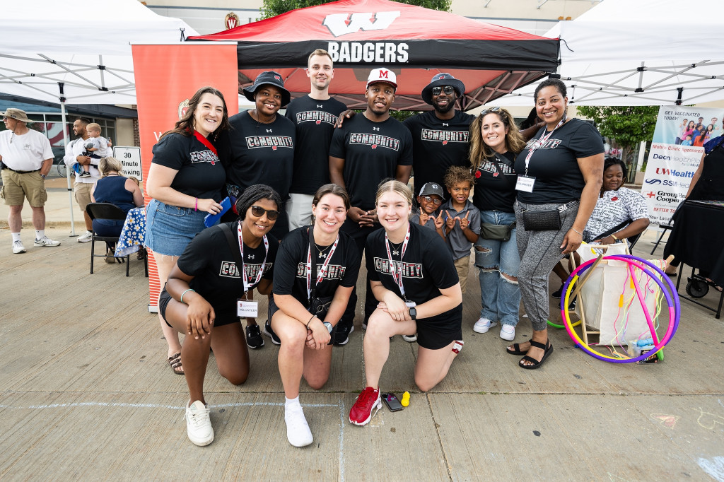 A group of people pose photo in two rows. They're wearing black T-shirts with the word 