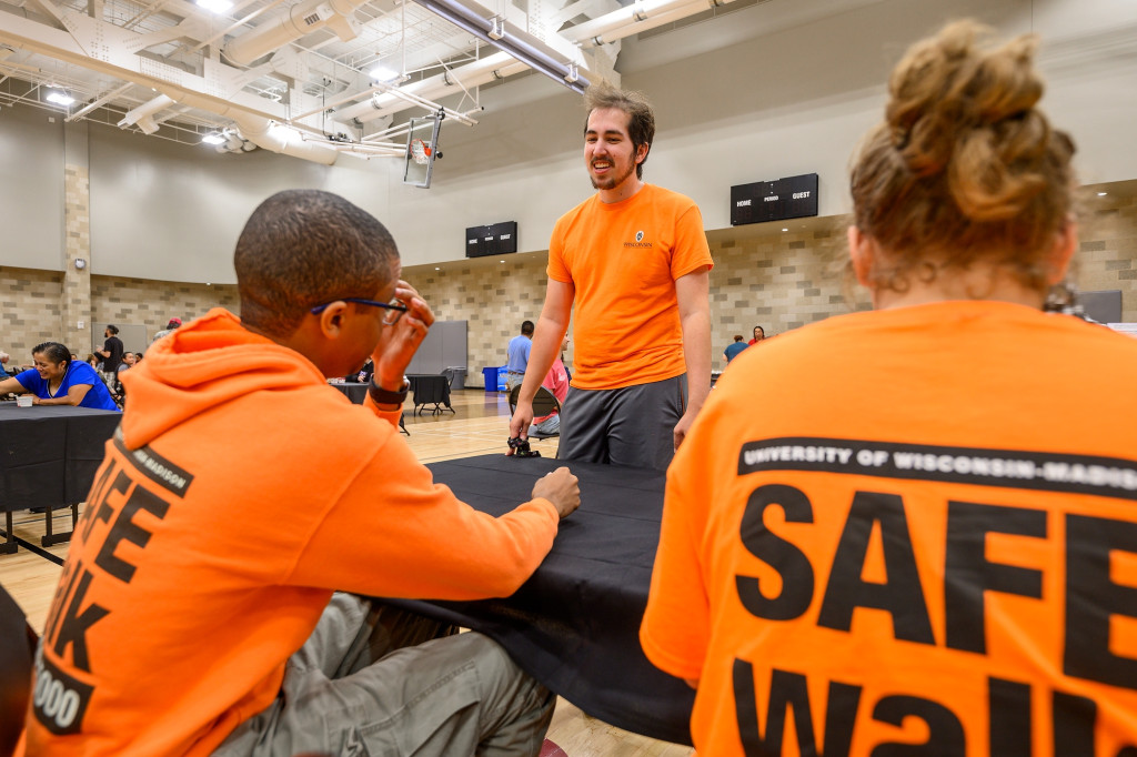 People in orange Safe Walk shirts talk.