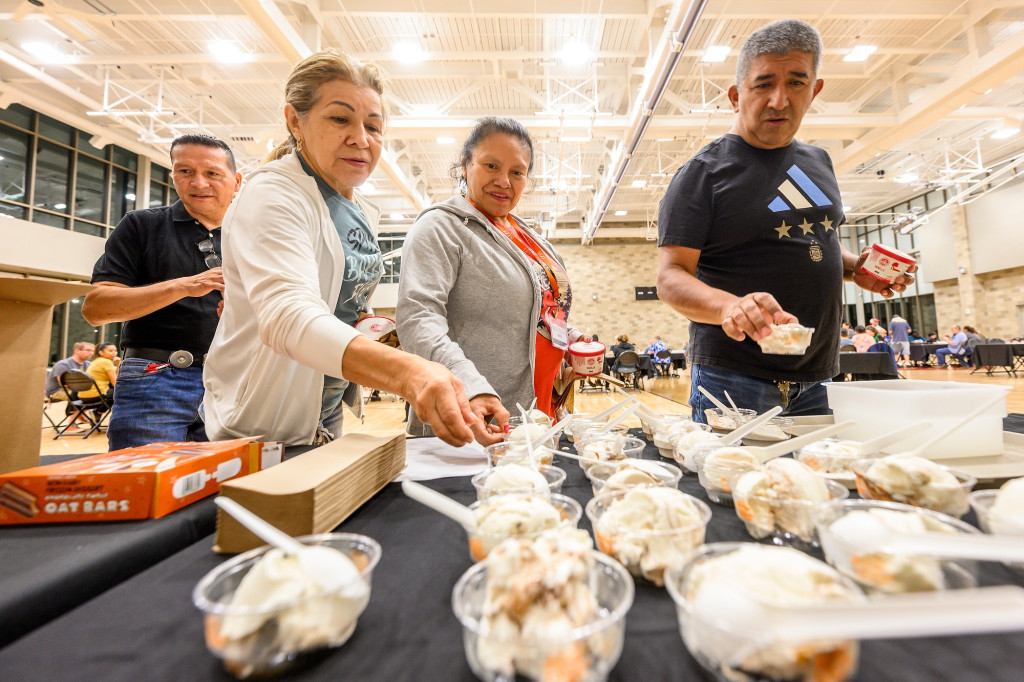 People survey a table filled with bowls of ice cream.