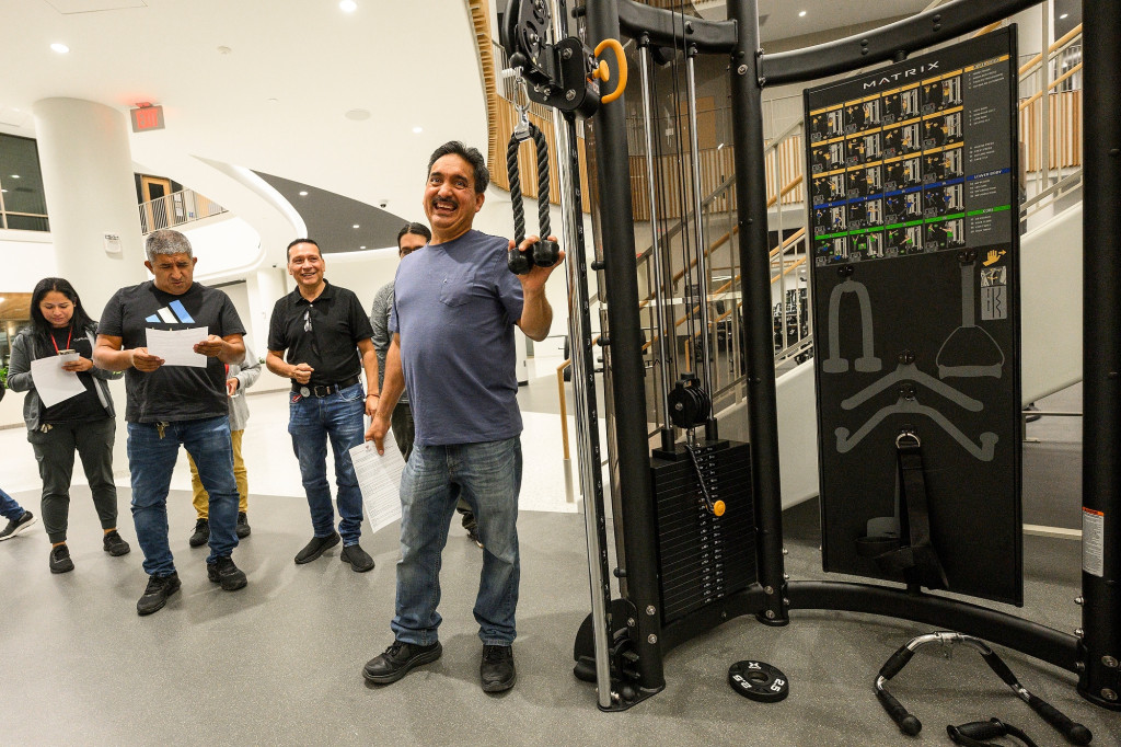 People walk around a room filled with workout equipment.