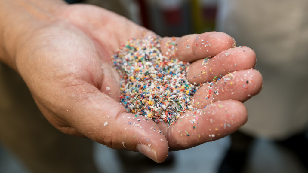 Photo of a hand with the palm open and holding a small pile of colorful shredded plastic pieces.