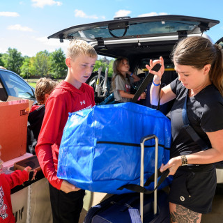 A student and her younger sibling work to load her belongings into a cart.