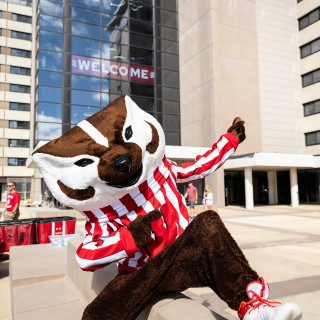 Bucky Badger plays air guitar outside a residence hall.