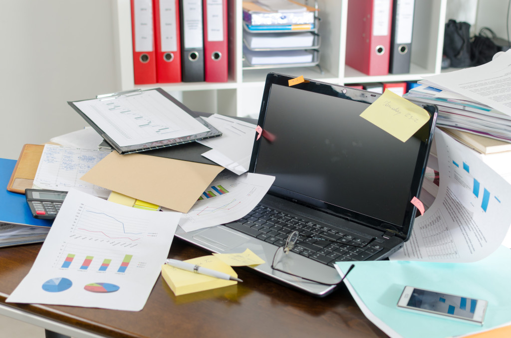 A desk cluttered with papers around a laptop.