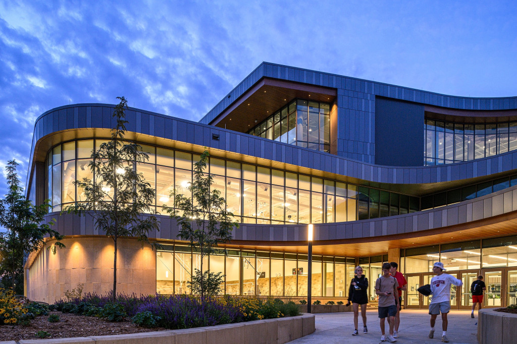 A large building with lots of windows is light inside, even as outside it darkens.