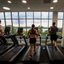 People run on treadmills while looking out the window.