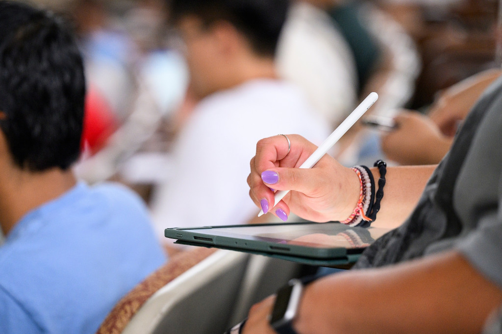 A close shot of a hand with a stylus taking notes on a tablet.