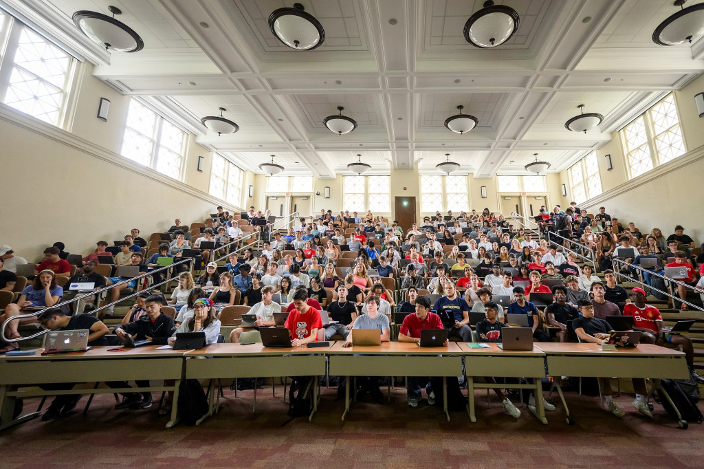 A view from the floor looking up into a full lecture hall with stadium seeting.