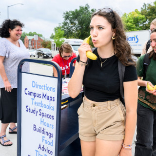 Cerro pretends to use a banana as a phone while standing outside. Other students are also picking up bananas.