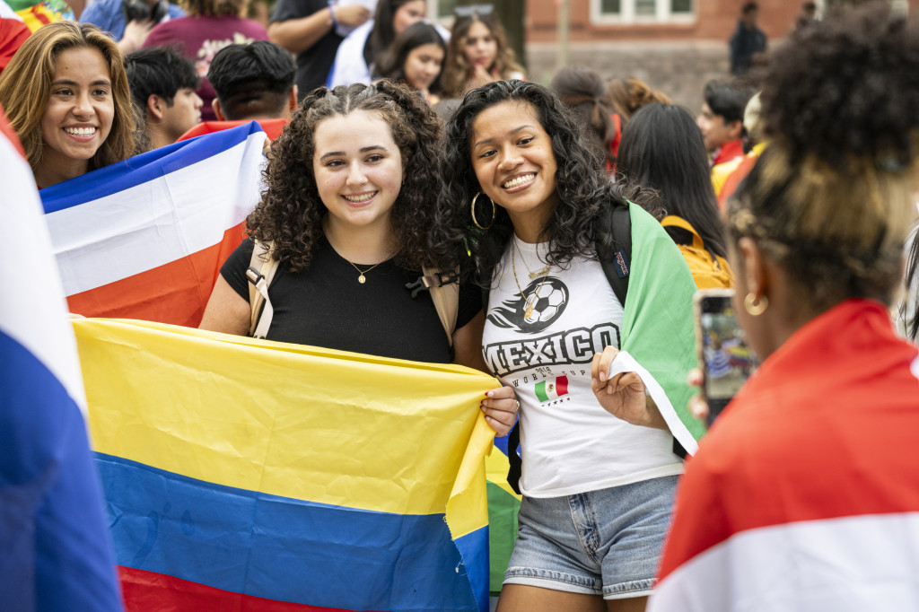 Two people are arm in arm, while holding up flags.