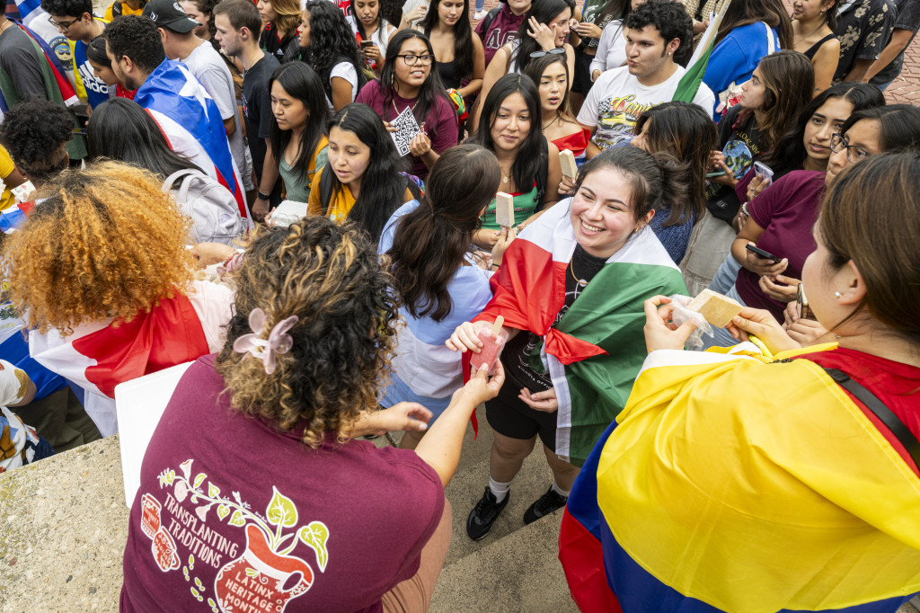 A woman in a crowd receives a frozen confection.