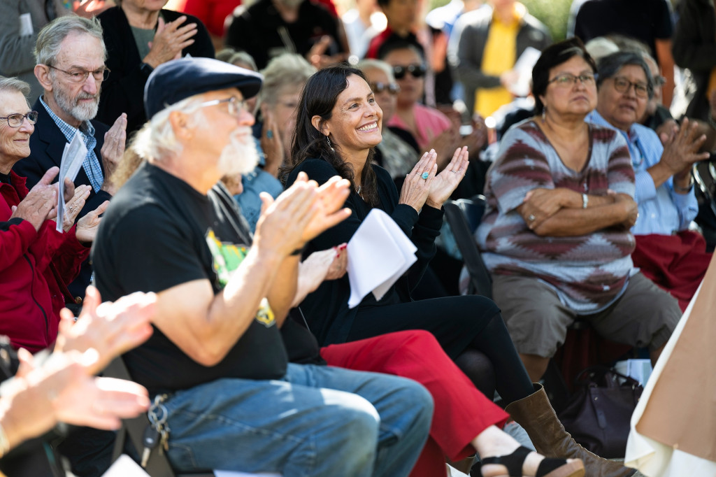 A woman in the audience applauds.