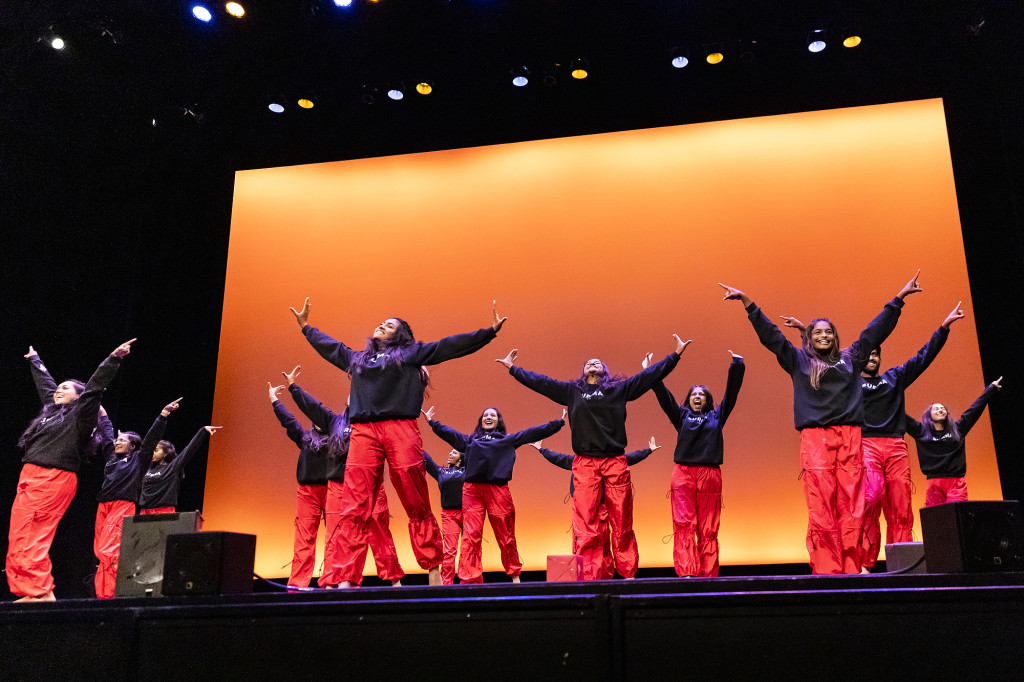 A group of people stand on stage and raise their arms.