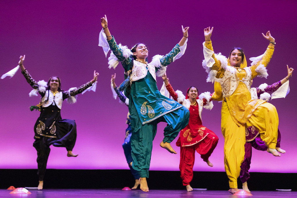 People on stage dance in traditional costumes.