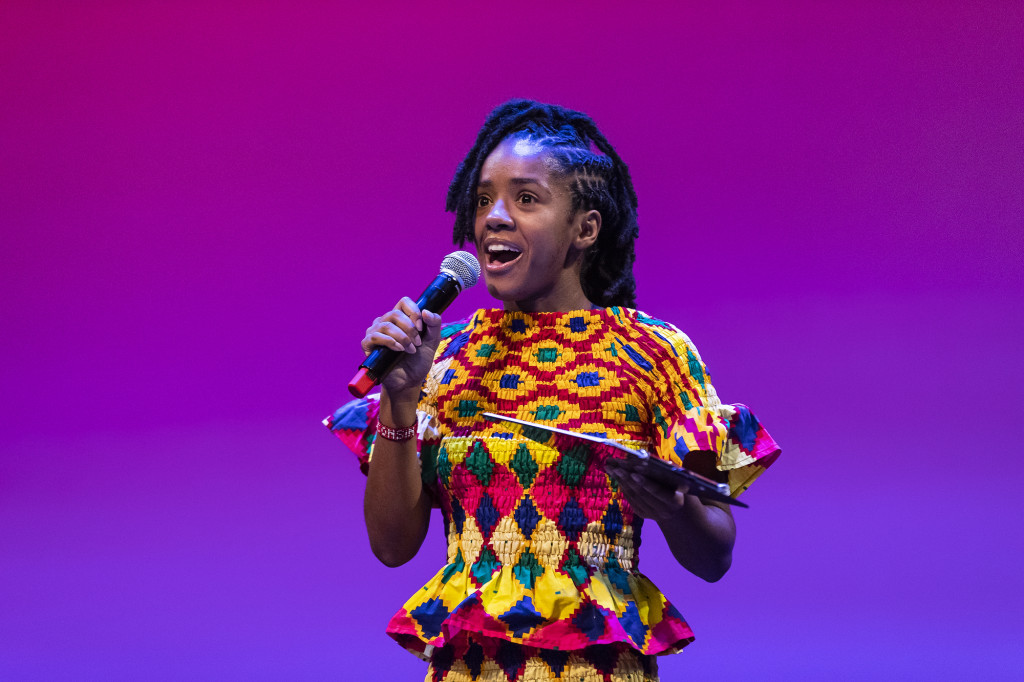 A woman on stage talks in a microphone.