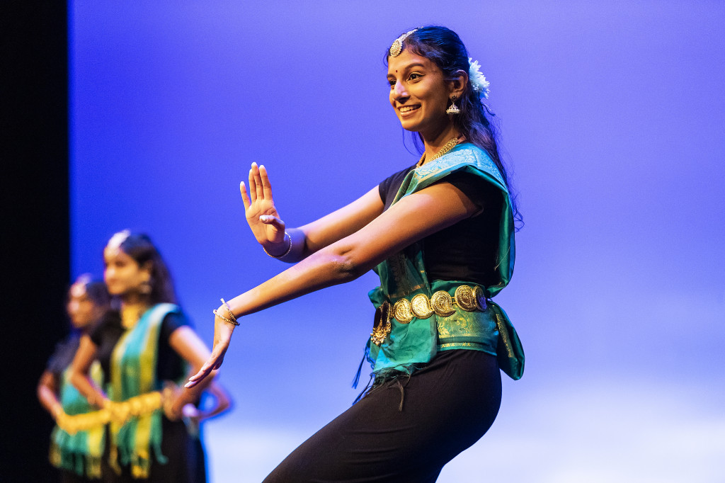 A dancer smiles and moves her arms elegantly.