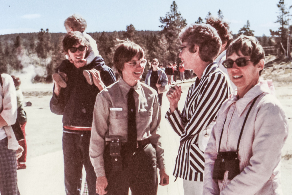 Faded 1980s photo showing a younger Monica Turner wearing a uniform while conversing with a group of people